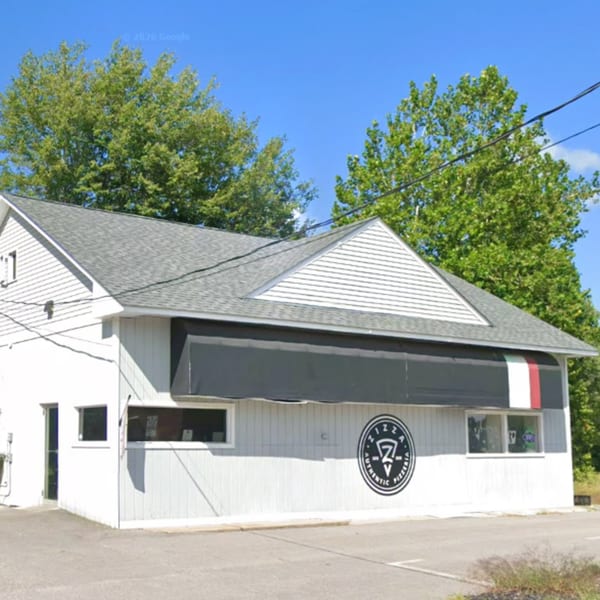 Exterior of a white pizzeria building with a black awning and an Italian flag stripe.